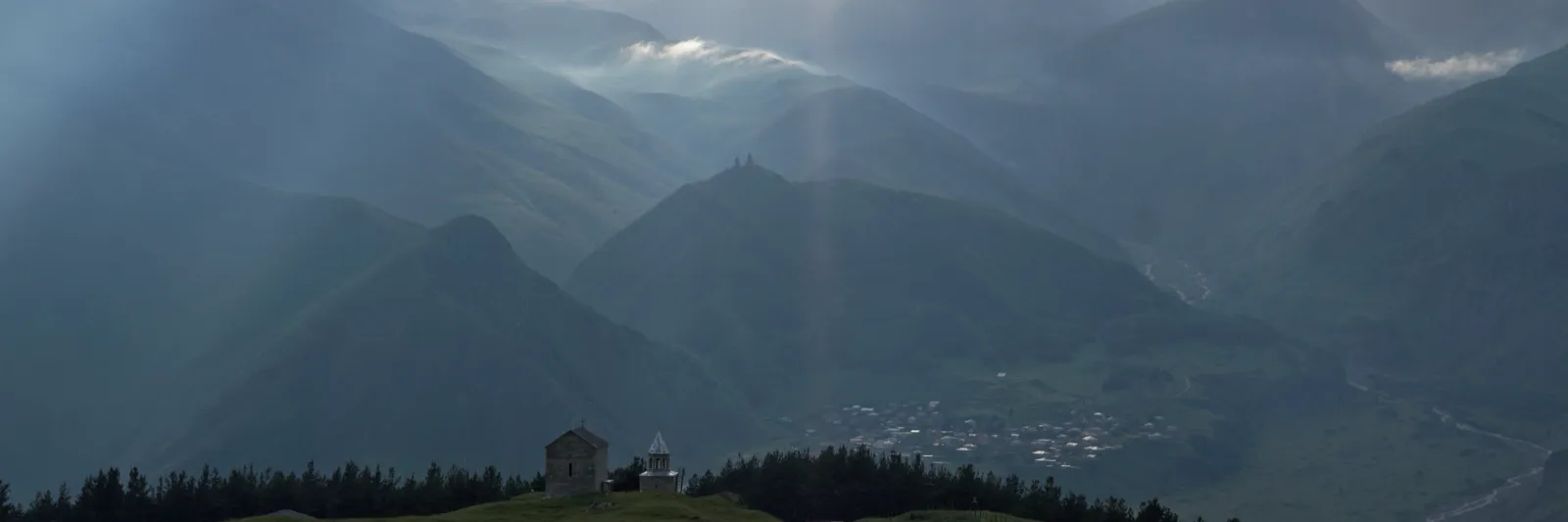 Berg och dalar kring Kazbegi i Kaukasus, med Gergetikyrkan